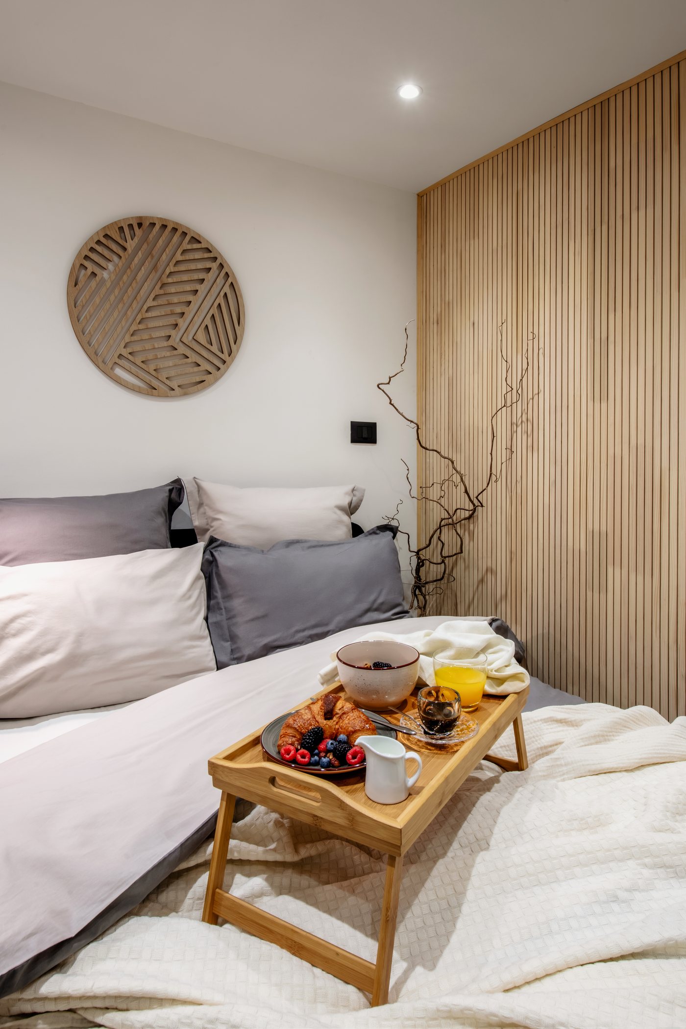 Vassoio della colazione sul letto, con la parete in legno e il tondo decorativo