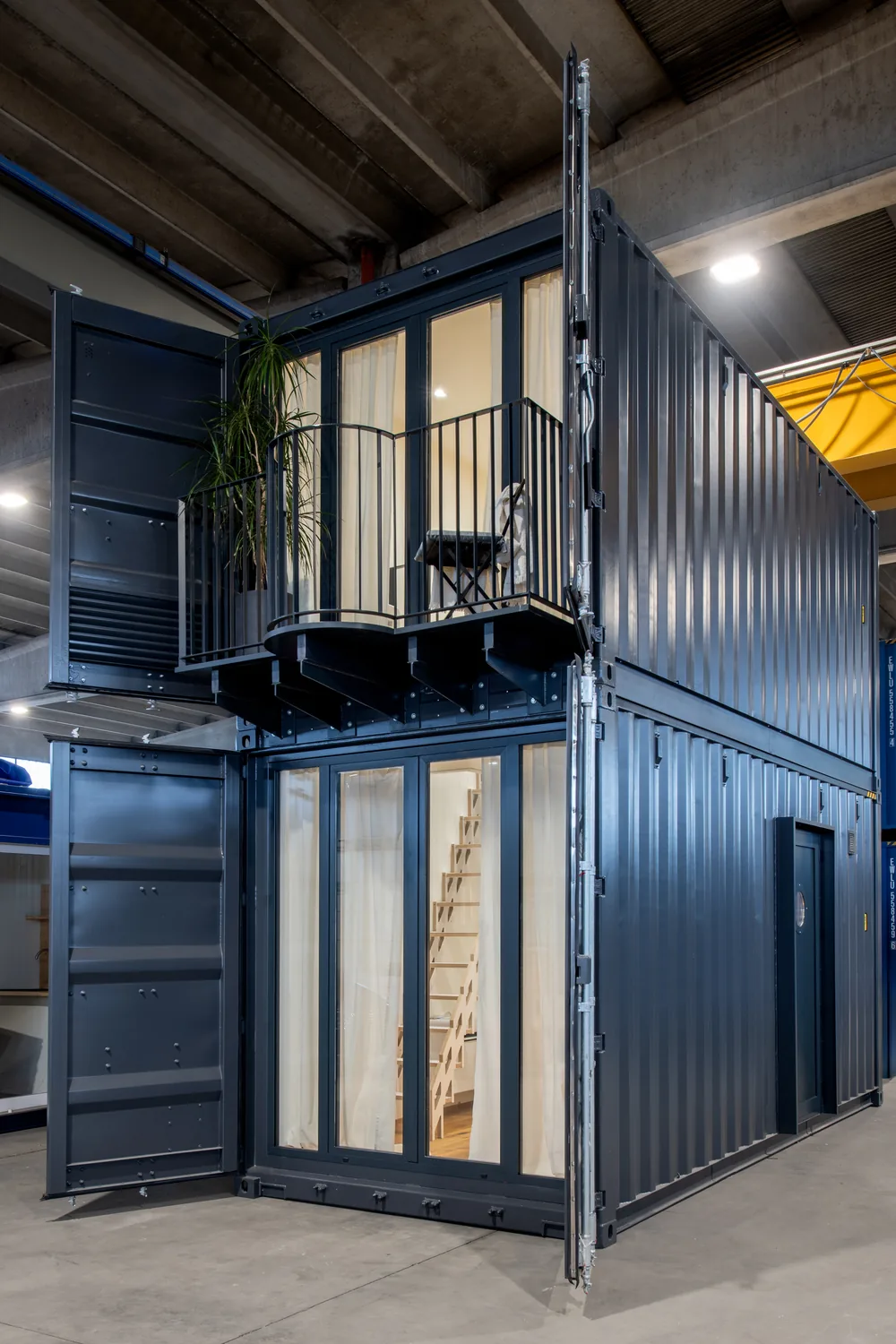Il container a due piani in grigio antracite con balcone e tende chiare, in officina
