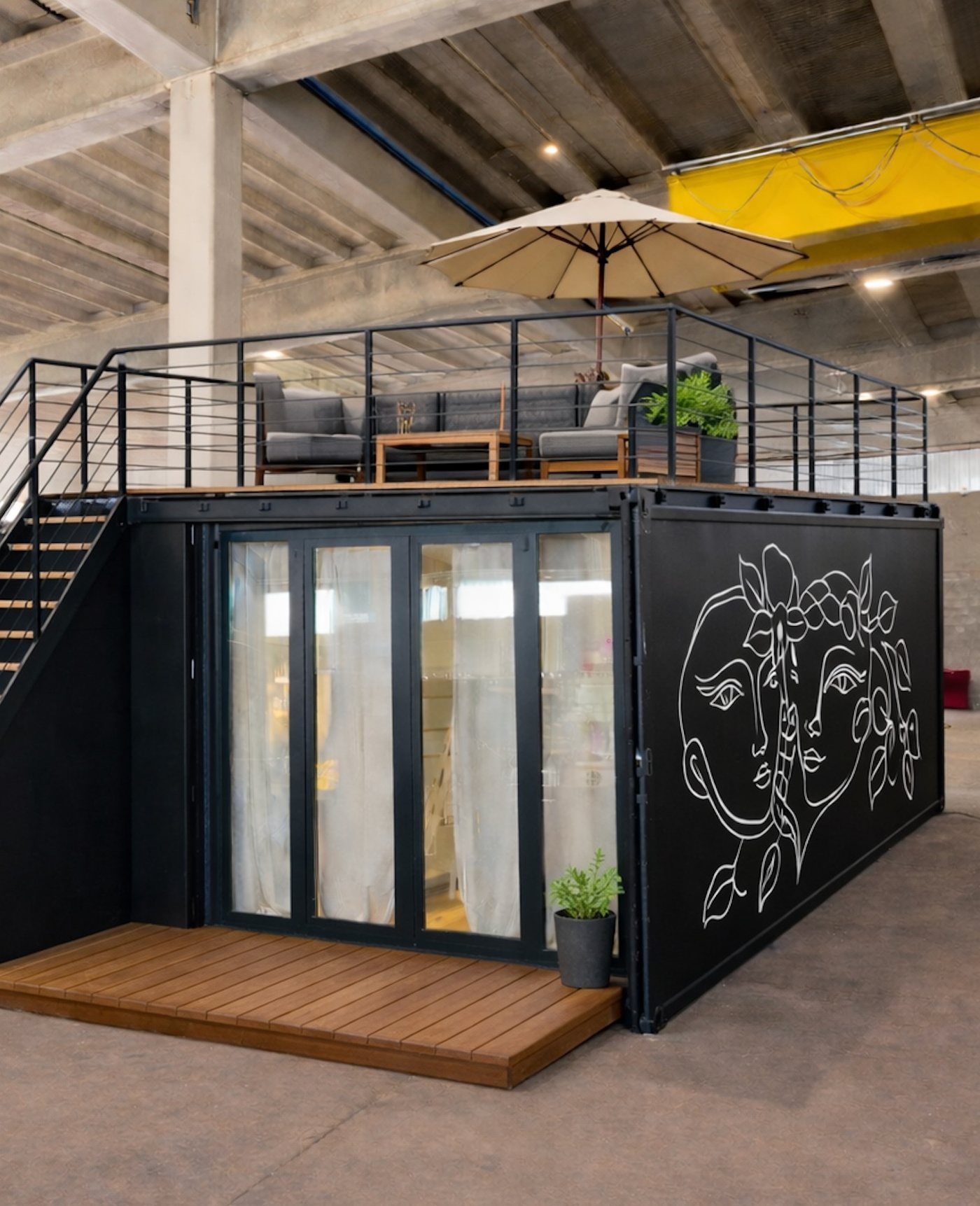 Unità singola da 20 piedi con terrazza sul tetto, ombrellone e un disegno a linee sulla parete, in officina